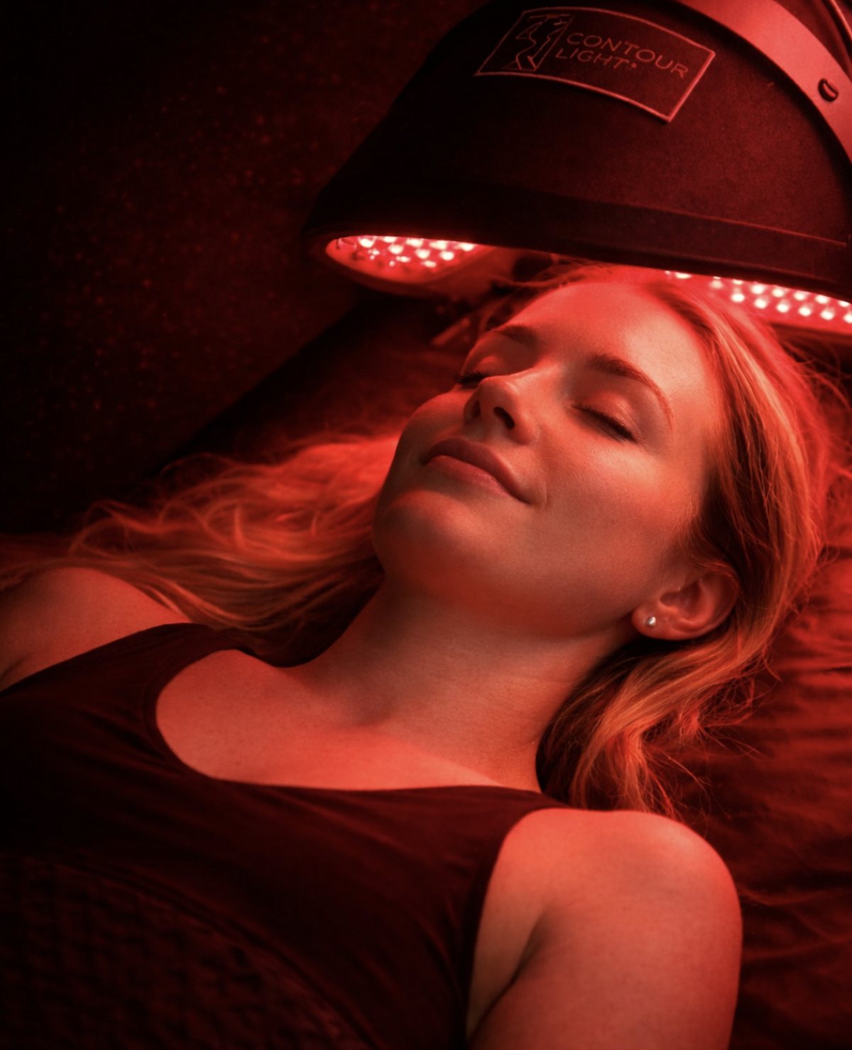 A member relaxing under a Contour Light red light therapy device at Red Light Method Commack.