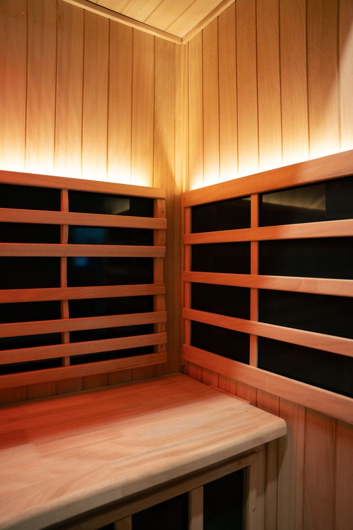 Inside the far infrared sauna, cedar benches and heater panels warmly lit.