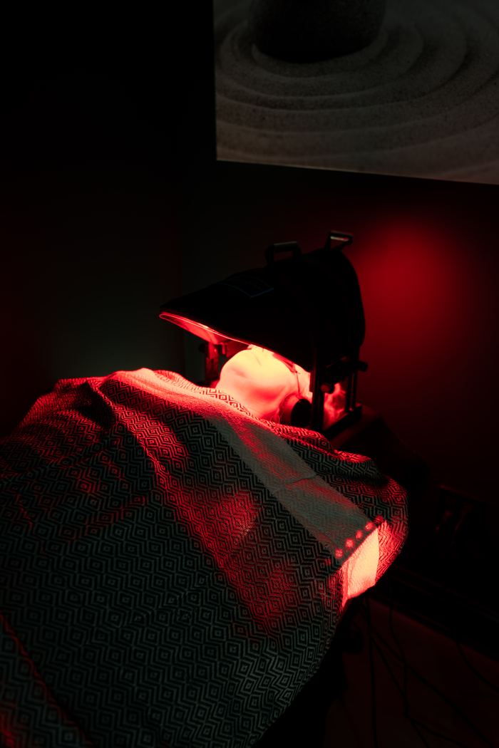A member resting under the red light panel, wrapped in a Red Light Method throw.